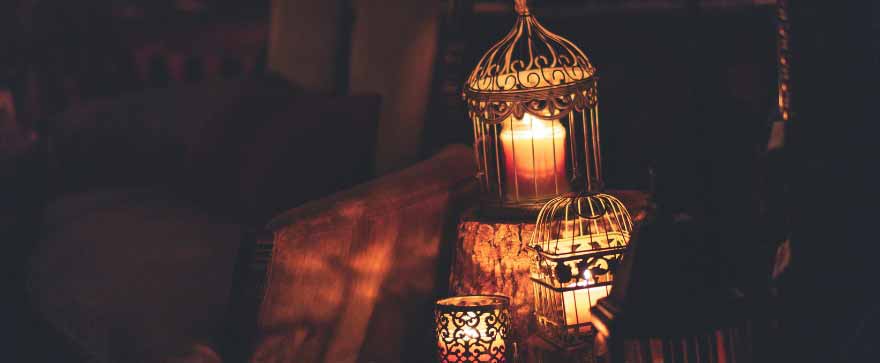 Ornate metal candle cages with burning candles in a dark setting, symbolizing Ramadan.