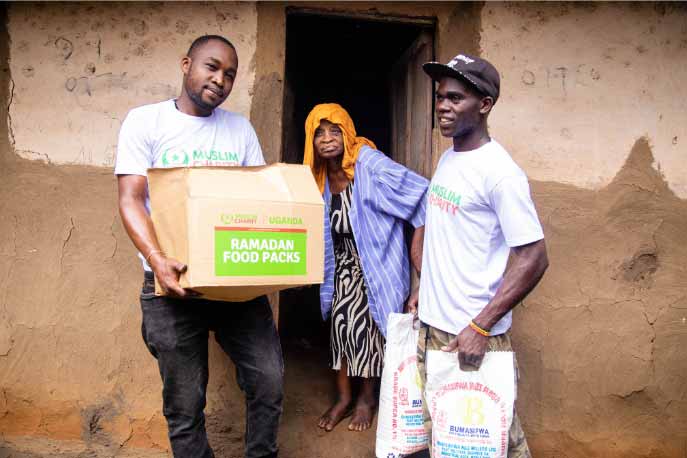 Volunteers distribute Ramadan charity food packs to a family at a rural home in Uganda.