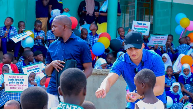 Two men stand together as one hands a chocolate to a child, smiling and sharing a joyful moment.
